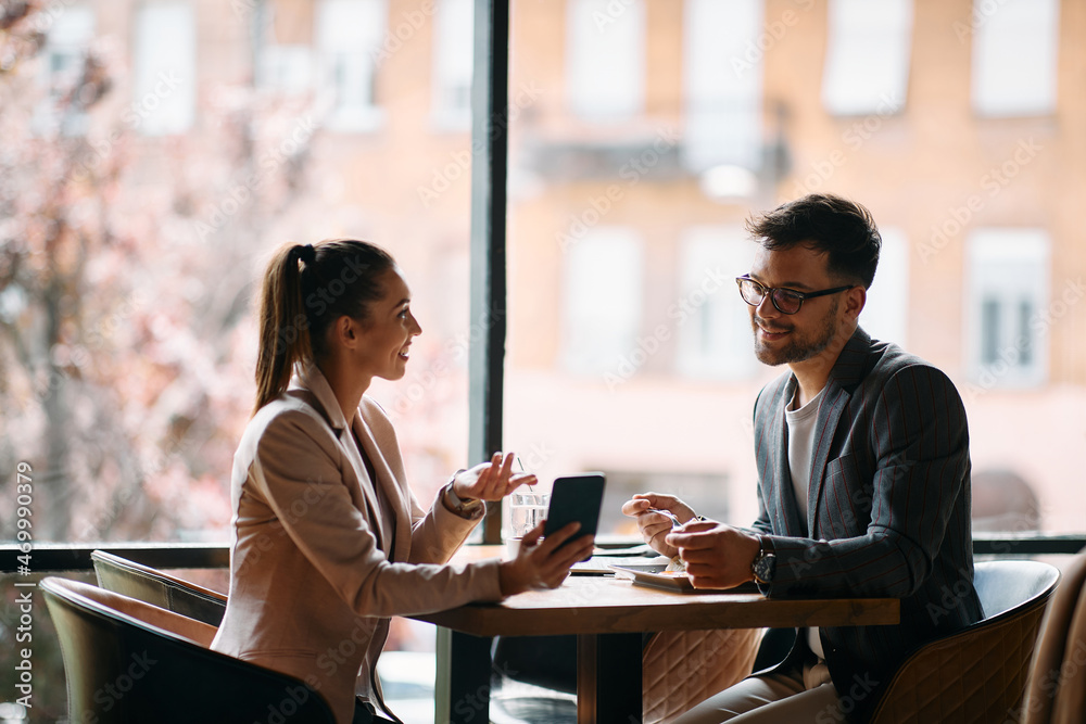 Happy business colleagues use smartphone during casual meeting in cafe.