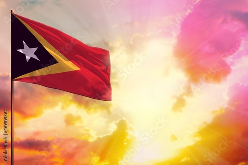 Fluttering Timor-Leste flag in top left corner mockup with the space for your text on beautiful colorful sunset or sunrise background.
