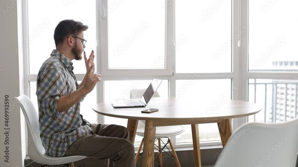man rejoices in success working at a laptop, dances energetically at home at his desk. Successful online business man rejoices in success working at a laptop, dances energetically at home at his desk. Successful online business