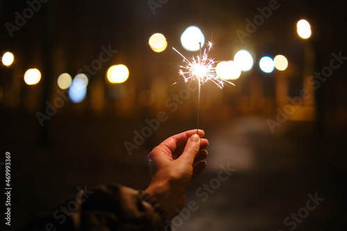Sparklers burning in the hands of a girl close-up at night. Christmas and New Year mood with lights. Time to celebrate and light up fireworks