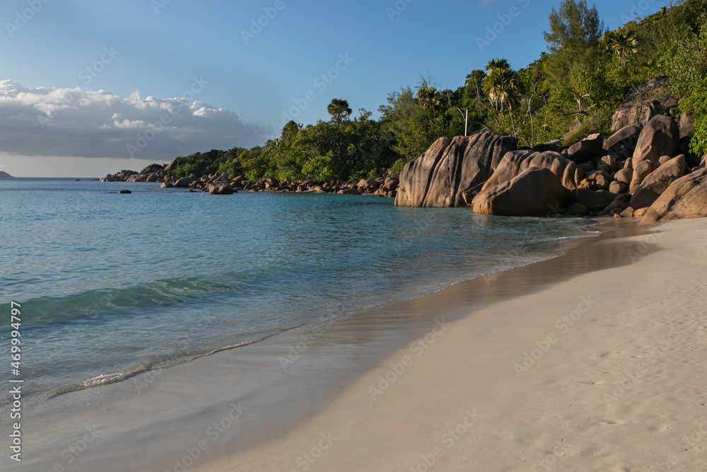 Pacifying seascape of Lazio beach on the island of Praslin in the Seychelles. Perfect sandy coastline is washed by the turquoise waters of the Indian Ocean. The blue lagoon is guarded with huge rocks