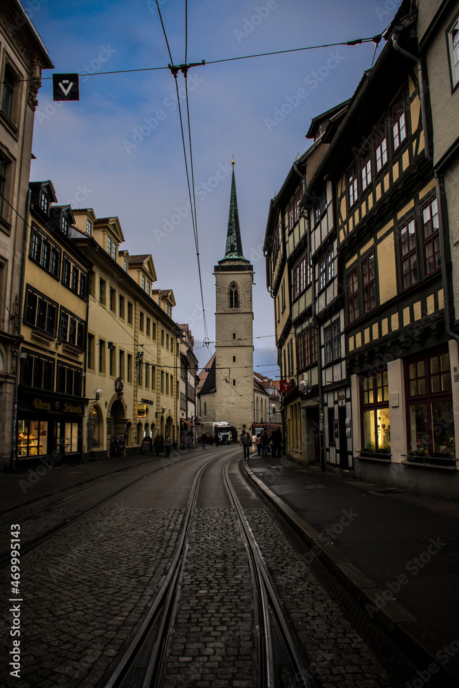 Street with a rail and a church at the background in a dark mood. Erfurt, Germany
