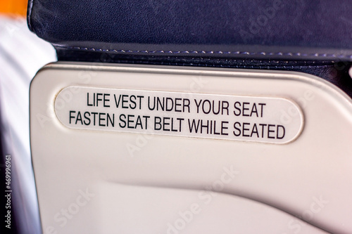 Attention announcement for passengers about emergency life vest and the seatbelt on the seat back inside the airplane cabin. Concept of takeoff, turbulence warning and safe landing of the aircraft. photo