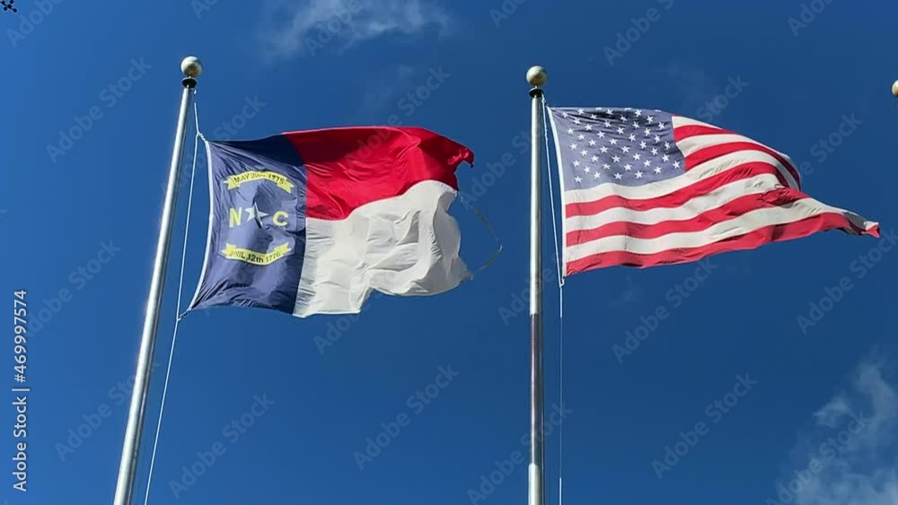 NC and USA flags blowing against a blue sky NC and USA flags blowing against a blue sky