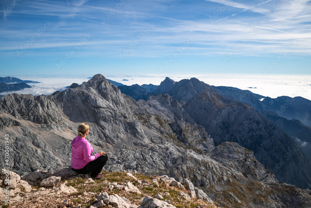 Female hiker sitting and relaxing on a mountain and enjoying beautiful view.