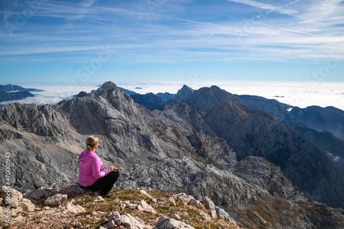 Female hiker sitting and relaxing on a mountain and enjoying beautiful view.