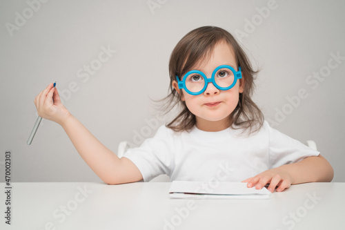 The doctor tells how to treat everyone. The child is playing doctor funny. A kid with glasses writes something on a piece of paper