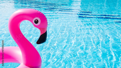 Pink pool. Pink inflatable flamingo in water for summer beach background. Funny bird toy for kids. © Maksym