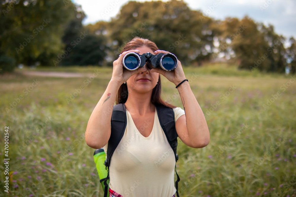 Woman hiking on pastures in the mountains and using binoculars Woman hiking on pastures in the mountains and using binoculars