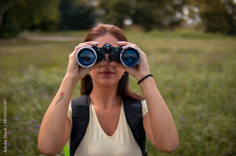 Woman hiking on pastures in the mountains and using binoculars Woman hiking on pastures in the mountains and using binoculars