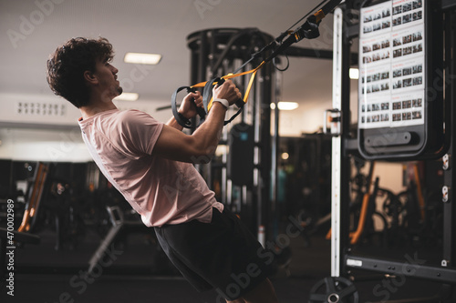 a young man exercising with a TRX inside a gym. photo