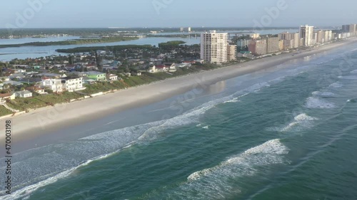 Aerial pan of Florida east coast barrier island beachfront community Wilbur By The Sea, showing beach, ocean surf, residential houses with sea walls, and the Atlantic Intracoastal Waterway. photo
