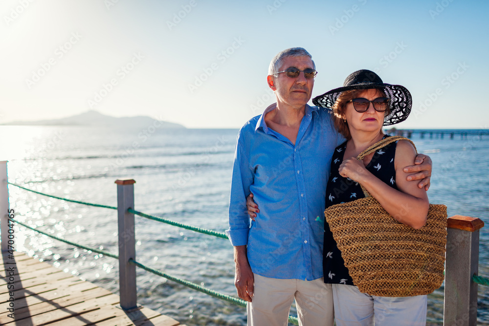Senior family couple walking on pier by Red sea. Retired people enjoying vacation in Egypt enjoying landscape.