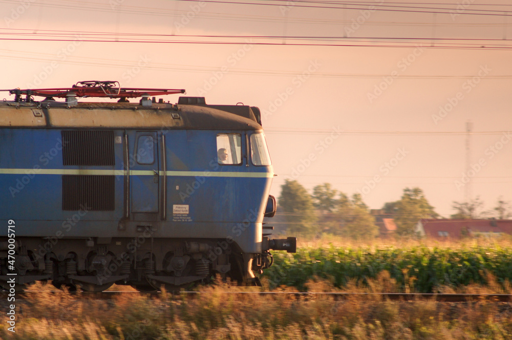 Polska elektryczna lokomotywa towarowa jadąca wczesnym wieczorem w stronę zachodzącego Słońca. - obrazy, fototapety, plakaty 