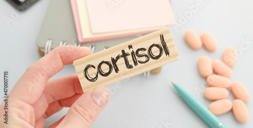 Doctor holds wooden block in his hands with text CORTISOL photo