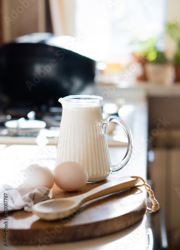 Fresh milk and eggs on wooden board in real home kitchen interior with natural light