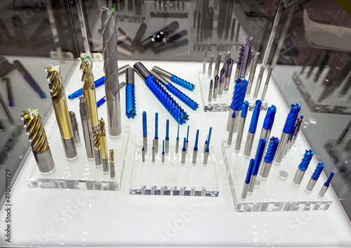 display case with machining tools, drills, milling cutters, reamers of different diameters with multilayer titanium coatings in gold and blue, on methacrylate supports photo