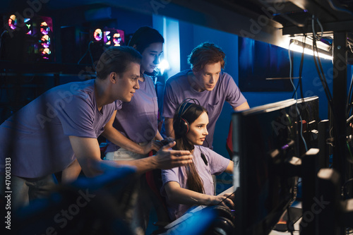 Two guys and girl at the computer club giving support to their friend during her game