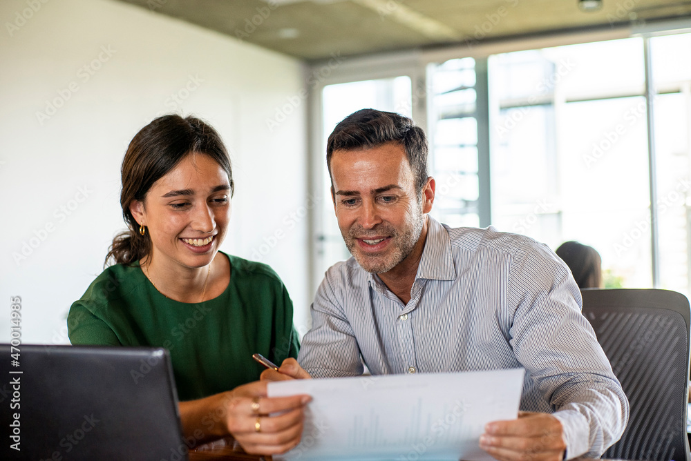 Obraz premium Smiling young woman and mature man working in office