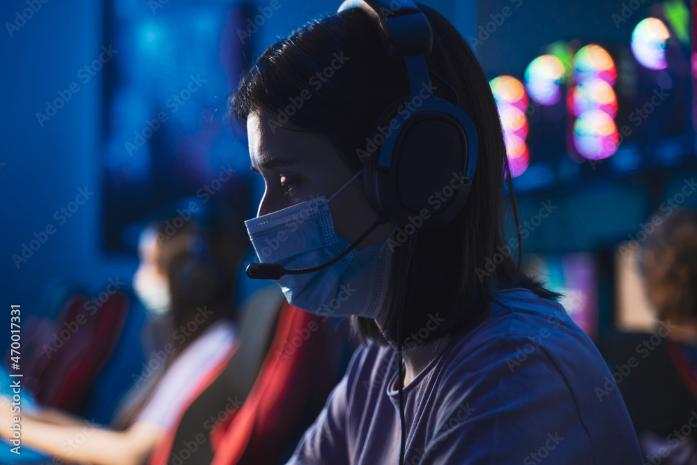 Girl member wearing protective mask playing at the computer international tournament Girl member wearing protective mask playing at the computer international tournament