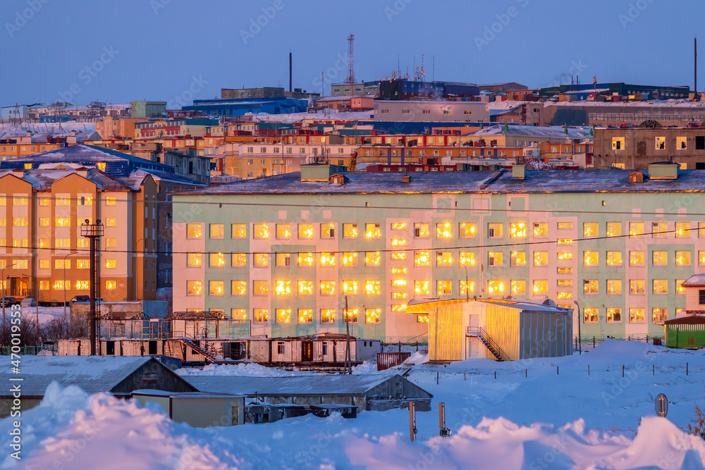 Winter morning cityscape. Northern city in the Arctic. Multi-colored buildings. In the foreground is a school building. Sunlight is reflected in the windows. Anadyr, Chukotka, the Far North of Russia.
