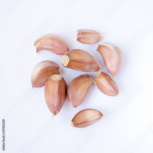 Close-up of a group of garlic cloves on a white background, top view.
