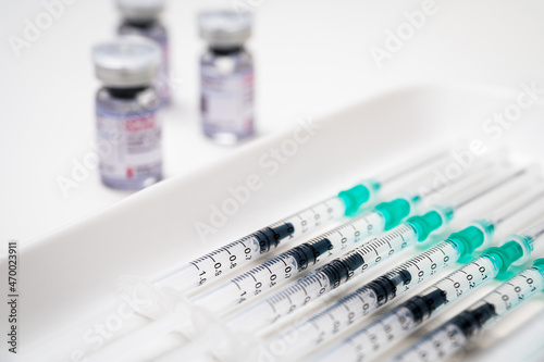Coronavirus vaccination against SARS-CoV-2. Medical syringes with COVID-19 vaccine on a medical tray and different glass vials in the background.