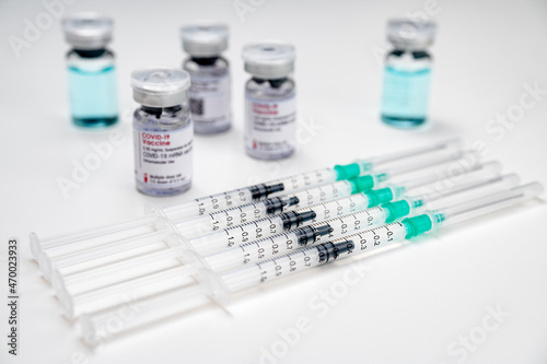 Coronavirus vaccination against SARS-CoV-2. Medical syringes with COVID-19 vaccine, and different glass vials in the background.