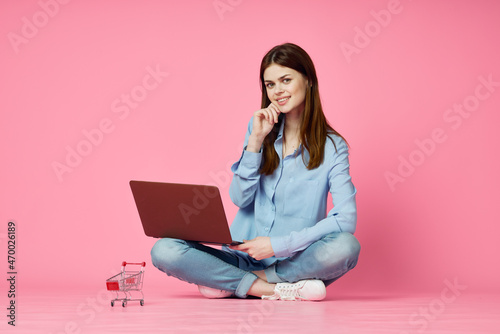 woman with laptop sitting on floor technology internet shopping pink background