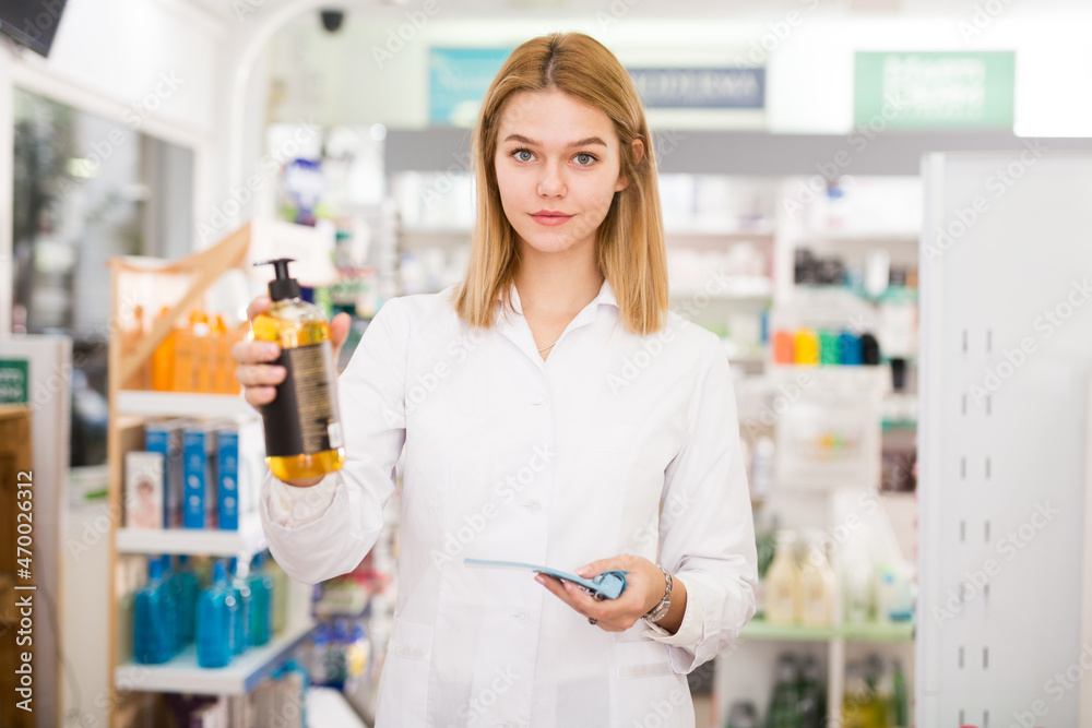 Portrait of smiling pleasant positive female druggist in white coat working in pharmacy. High quality photo