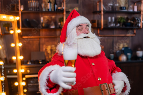 Santa Claus drinks beer while sitting in a leather armchair