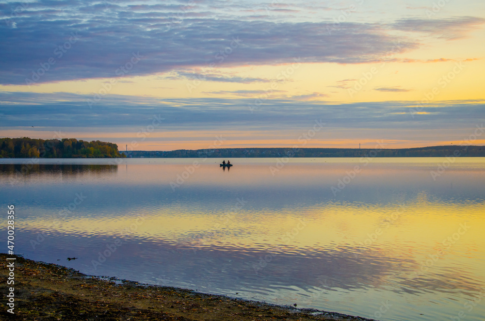 Fishermen in a boat in the lake at dawn.