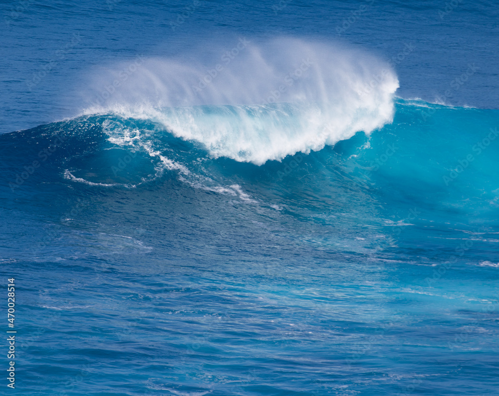 Surfing giant waves in the blue water of Maui Hawaii