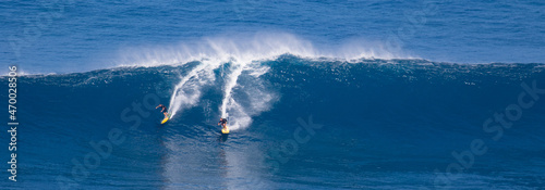 Surfing giant waves in the blue water of Maui Hawaii
