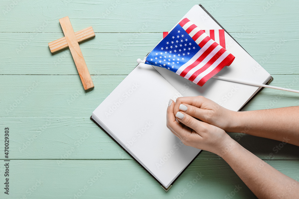 Fototapeta premium Woman with Holy Bible, USA flag and cross on green wooden background