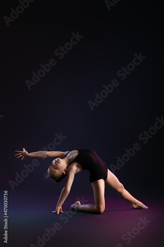 Little girl doing gymnastics on dark background