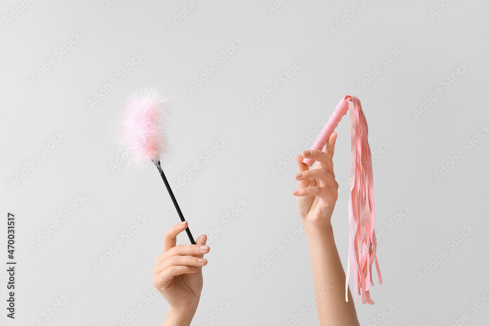 Female hands with sex toys on light background Female hands with sex toys on light background