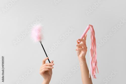 Female hands with sex toys on light background