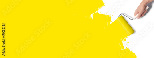 白い背景に、ローラーで黄色いペンキを塗っている手のグラフィック素材