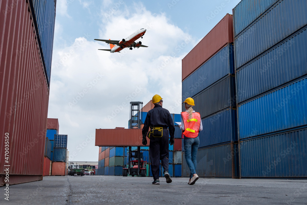 © Summit Art Creations - Industrial worker works with co-worker at overseas shipping container port . Logistics supply chain management and international goods export concept .