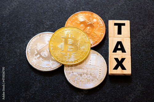 Fotografie Cryptocurrencies with TAX word on dark wood background