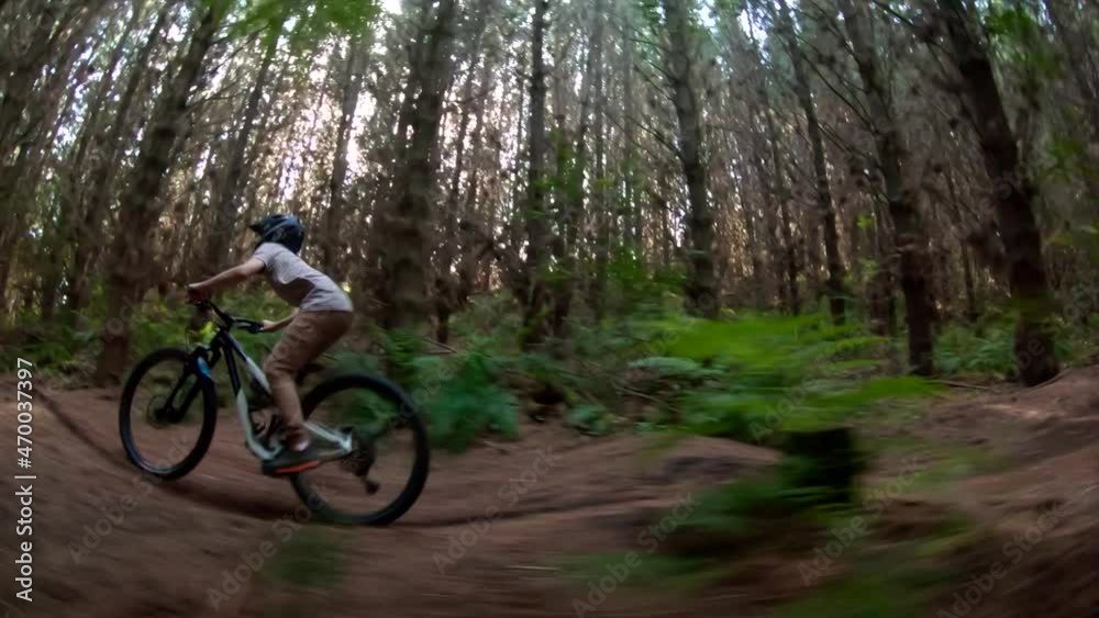 Kid on forest mountain bike track pumping speed on bicycle, bright light rays Kid on forest mountain bike track pumping speed on bicycle, bright light rays