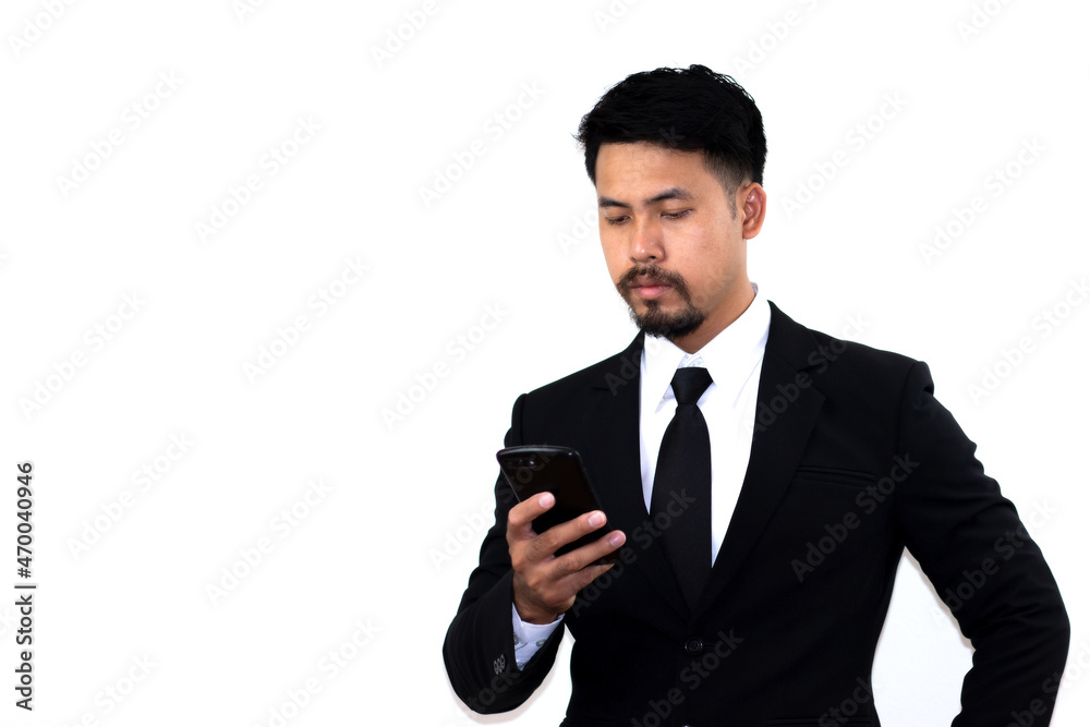 A young businessman in a black suit takes mobile messaging in corporate chats seriously. Empty space for text. White background. A young businessman in a black suit takes mobile messaging in corporate chats seriously. Empty space for text. White background.