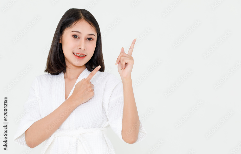 Portrait closeup studio shot of Asian black hair female model in rope stand smiling look at camera pointing two fingers at empty copy space presenting showing advertising product on white background Portrait closeup studio shot of Asian black hair female model in rope stand smiling look at camera pointing two fingers at empty copy space presenting showing advertising product on white background