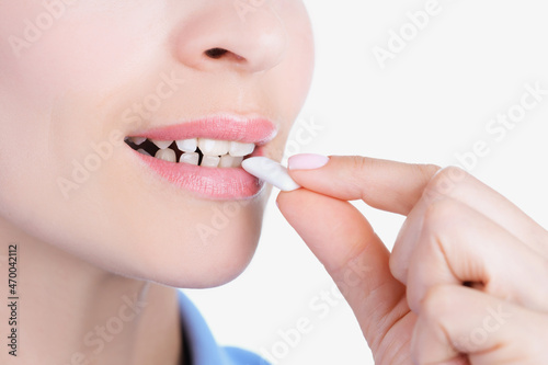 Womans face and female hand putting into mouth chewing gum