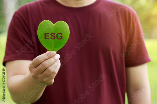 Fototapeta Naklejka Na Ścianę i Meble -  Man on redshirt hands holding heart-shaped leaves CSR ,ESG, Eco green sustainable living, environmental, social and corporate governance. earth day, world environment day, responsible consumption,