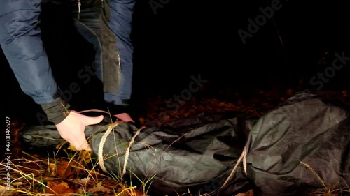 Killer and corpse.Crime scene. Murder and crime concept. Maniac and victim in a black bag in a dark park.Maniac drags his dead victim in the night deserted park. The maniac drags the victim through photo