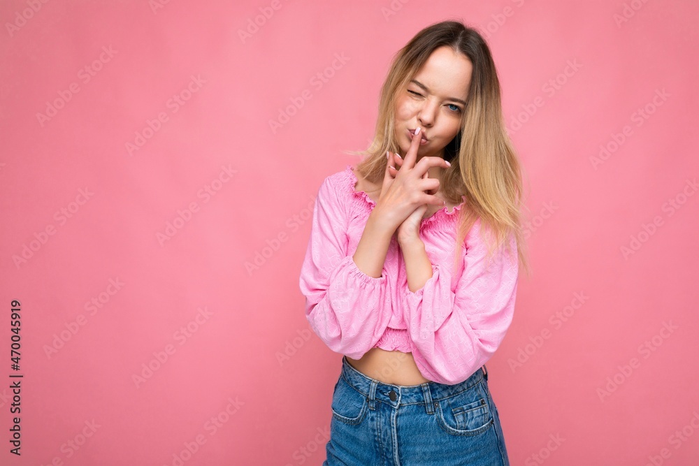 Portrait of young attractive beautiful pretty funny blonde woman in stylish pink crop top. Sexy carefree female person posing isolated near pink wall in studio with free space Portrait of young attractive beautiful pretty funny blonde woman in stylish pink crop top. Sexy carefree female person posing isolated near pink wall in studio with free space