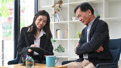 Smiling insurance agent offering health insurance to Asian elderly man.