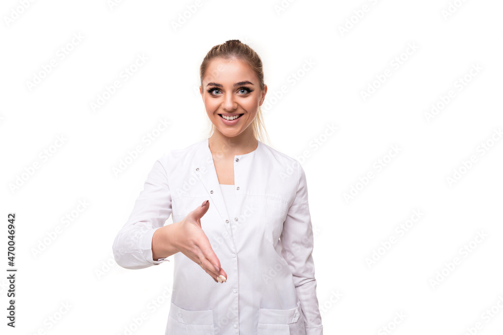 Photo of a beautiful pretty cute attractive positive smiling young blonde woman with a ponytail and makeup in a white medical coat of a nurse reaches out to say hello isolated on a white background Photo of a beautiful pretty cute attractive positive smiling young blonde woman with a ponytail and makeup in a white medical coat of a nurse reaches out to say hello isolated on a white background